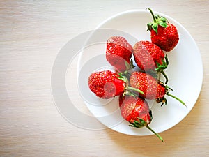 Ripe red strawberries on a white plate.