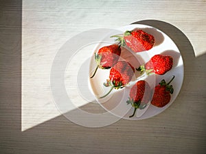 Ripe red strawberries on a white plate.