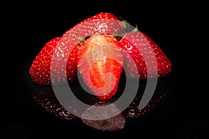 Ripe red strawberry on a black background with reflection