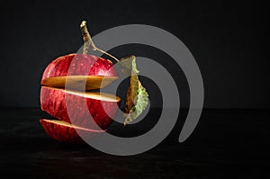 Ripe red sliced apple with a leaf in a levitation stack on a black concrete surface against a dark background. moody creative