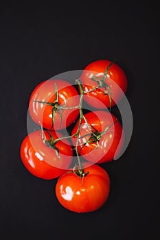 Ripe red tomatoes on black background, top view. The whole vegetable.