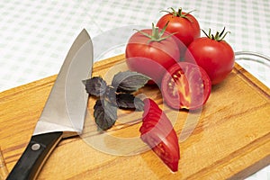 Ripe red tomatoes with a sprig of basil and knife