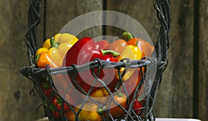 Ripe red, yellow and orange bell peppers in a wooden basket