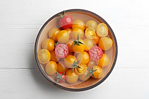Ripe red and yellow tomatoes in bowl on white wooden table