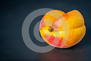 Ripe single apricot fruit cut open over dark background closeup