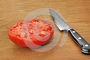 Ripe Sliced Red Tomato And Kitchen Knife On Wood Table