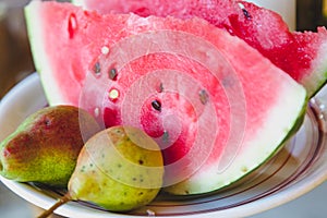 Ripe slices of watermelon and pears lie on plate