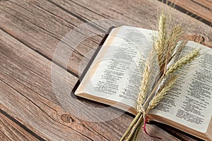 Ripe spring barley and an open Holy Bible Book on a rustic wooden table