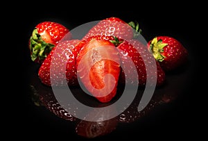 Ripe strawberries on a black background with reflection. Organic fruits