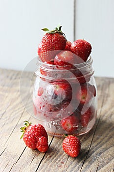 Ripe strawberries and cherries , glass jars. Wood background, rustic style.