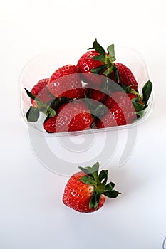 Ripe strawberries in a plastic package on a white background. Delicious fresh berries in a container for sale to