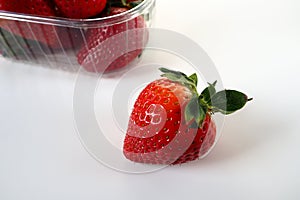 Ripe strawberries in a plastic package on a white background. Delicious fresh berries in a container for sale to