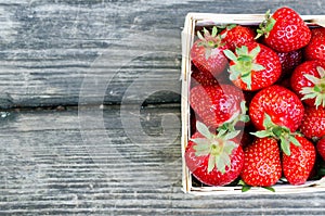Ripe strawberries in wooden box on wooden table