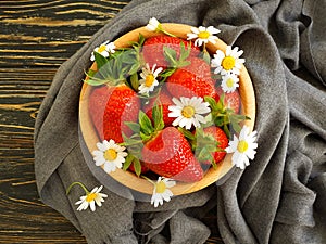 Ripe strawberry, chamomile flower on wooden backgrou photo