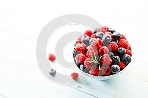 Ripe sweet blueberries and raspberries in a bowl. Closeup