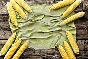 Ripe, sweet, fresh corn on cobs. Top view with copyspace on a brown rustic wooden table