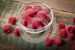 Ripe sweet raspberries in bowl on wooden table