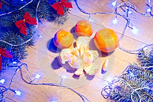 Ripe tangerines, New Year / Christmas tree with red bows and blue garland on the wooden background template