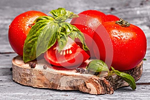 Ripe tomatoes with fresh basil leaves, black salt, and peppercorn