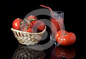 Ripe tomatoes and freshly squeezed tomato juice on a black background.