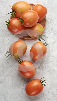 Ripe tomatoes on a plate and scattered on table top