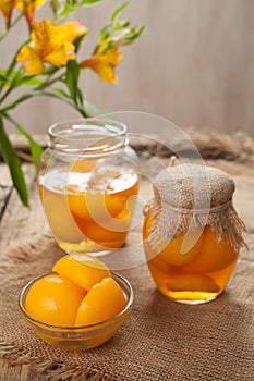 Ripe traditional canned peaches in glass jars with compote