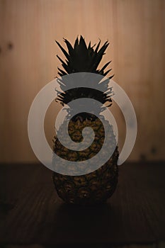 Ripe Tropical Pinapple on a wooden table with a wooden background. Tropical fresh healthy fruits. Backlighted pineapple