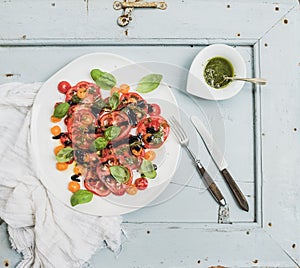 Ripe village heirloom tomato salad with olive oil and basil over light blue wooden background