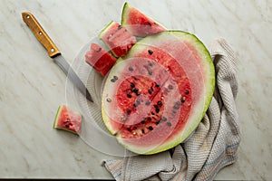 Ripe watermelon cut into slices on a light table by window, still life, top view