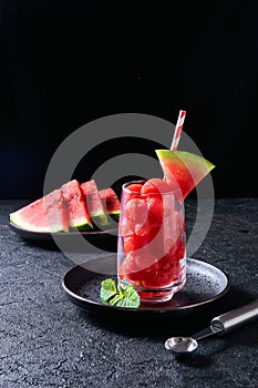 Ripe watermelon noisette balls in glass with mint on dark background. Summer dessert photo