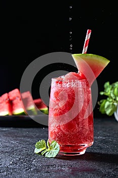 Ripe watermelon noisette balls with sada in glass and falling water drops on dark background. Refreshing summer drink photo