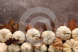 Ripe white pumpkins and dry leaves on grey textured table, flat lay. Space for text