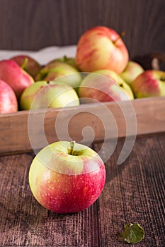 Ripe whole apple on the background of a fruit box on a wooden table. Local seasonal fruits. Vertical