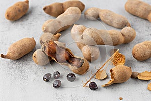 Ripe whole and shelled tamarind fruits with seeds closeup on stone background