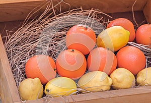 Ripe yellow lemons and orange oranges in a wooden box