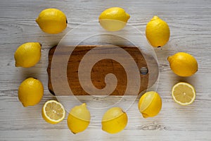 Ripe Yellow Organic Lemons and rustic board on a white wooden background, overhead view. Flat lay, top view, from above