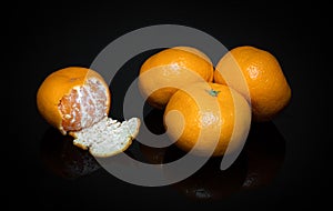 Ripe yellow tangerines or mandarins fruit on black background. Idea clementines dieta