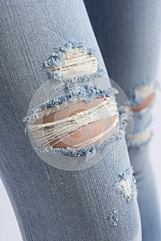 Ripped jeans on female`s legs. Closeup view.