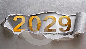 Ripped metallic paper revealling the year 2029 written in golden numbers on a silver background