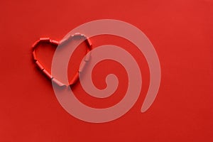 Ripped paper hole heart shaped on red paper background. Valentine`s day celebration concept