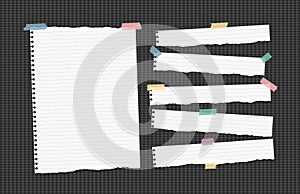 Ripped ruled note, notebook, copybook paper strips stuck with sticky tape, on black squared background.