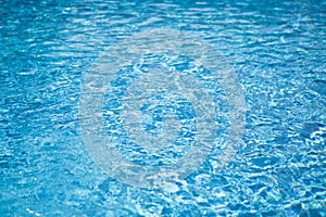 Ripple water in swimming pool with sun reflection. Blue water abstract background