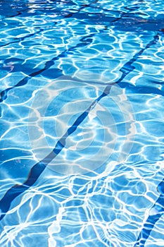 Ripple Water in swimming pool with sun reflection. Summer day at swimming pool. Background and texture concept.Vertical.