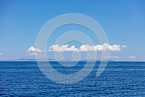 Rippled Aegean Sea, cloud on blue sky over Serifos island rocky land. Seascape, Cyclades Greece