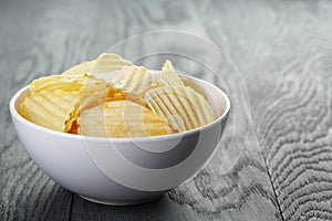 Rippled organic chips in white bowl on wooden