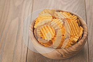 Rippled potato chips in wood bowl with copy space