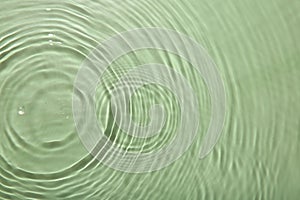 Rippled surface of clear water on light green background, top view