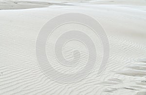 Rippled surface of white sand. Natural or abstract bright beige background. Sand texture