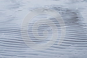 Rippled wet sand and water at the beach texture abstract background