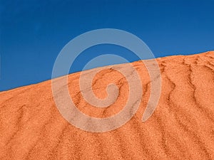 Ripples in the red sand desert and blue sky.